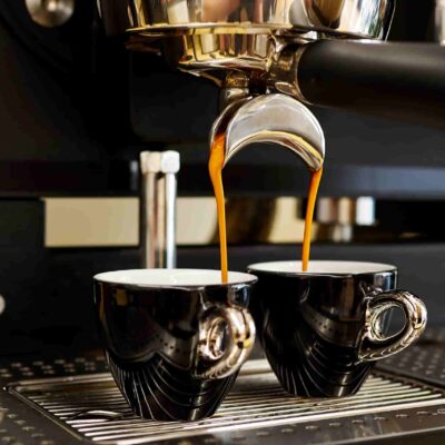 Espresso läuft aus dem Siebträger in zwei Tassen